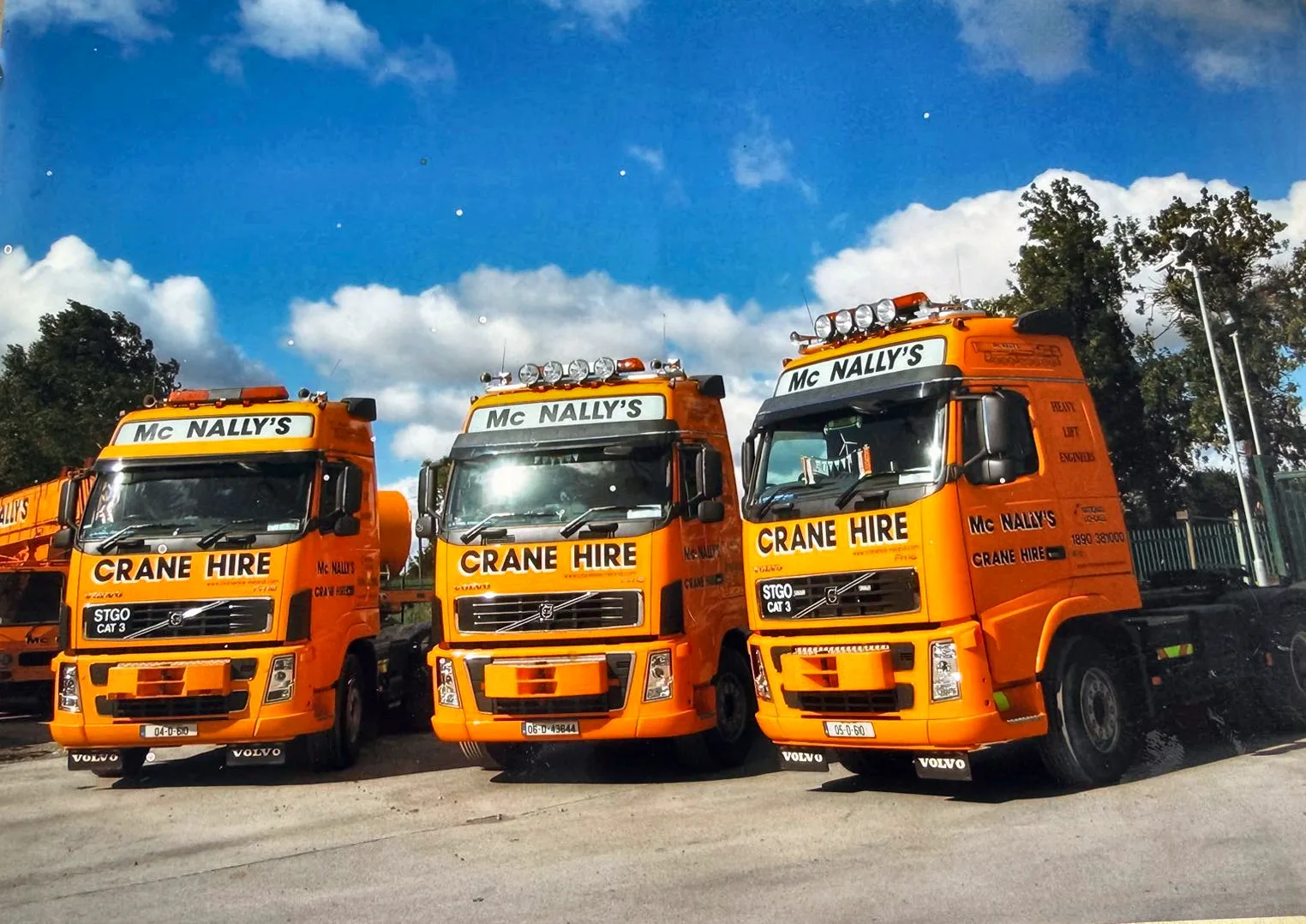 Archive photograph of three orange McNally’s crane trucks lined up