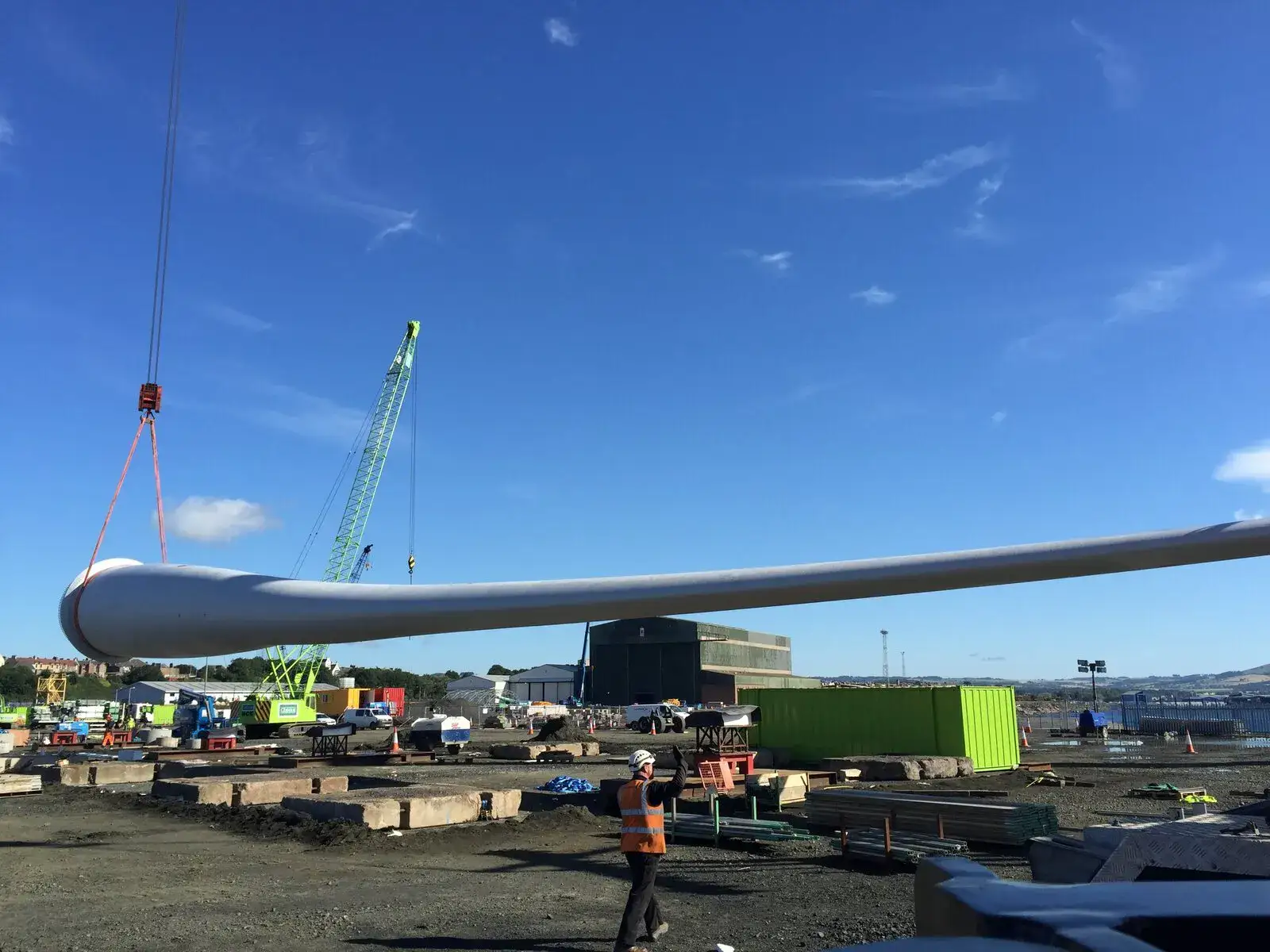 Turbine blade lifted horizontally with ground crew looking on