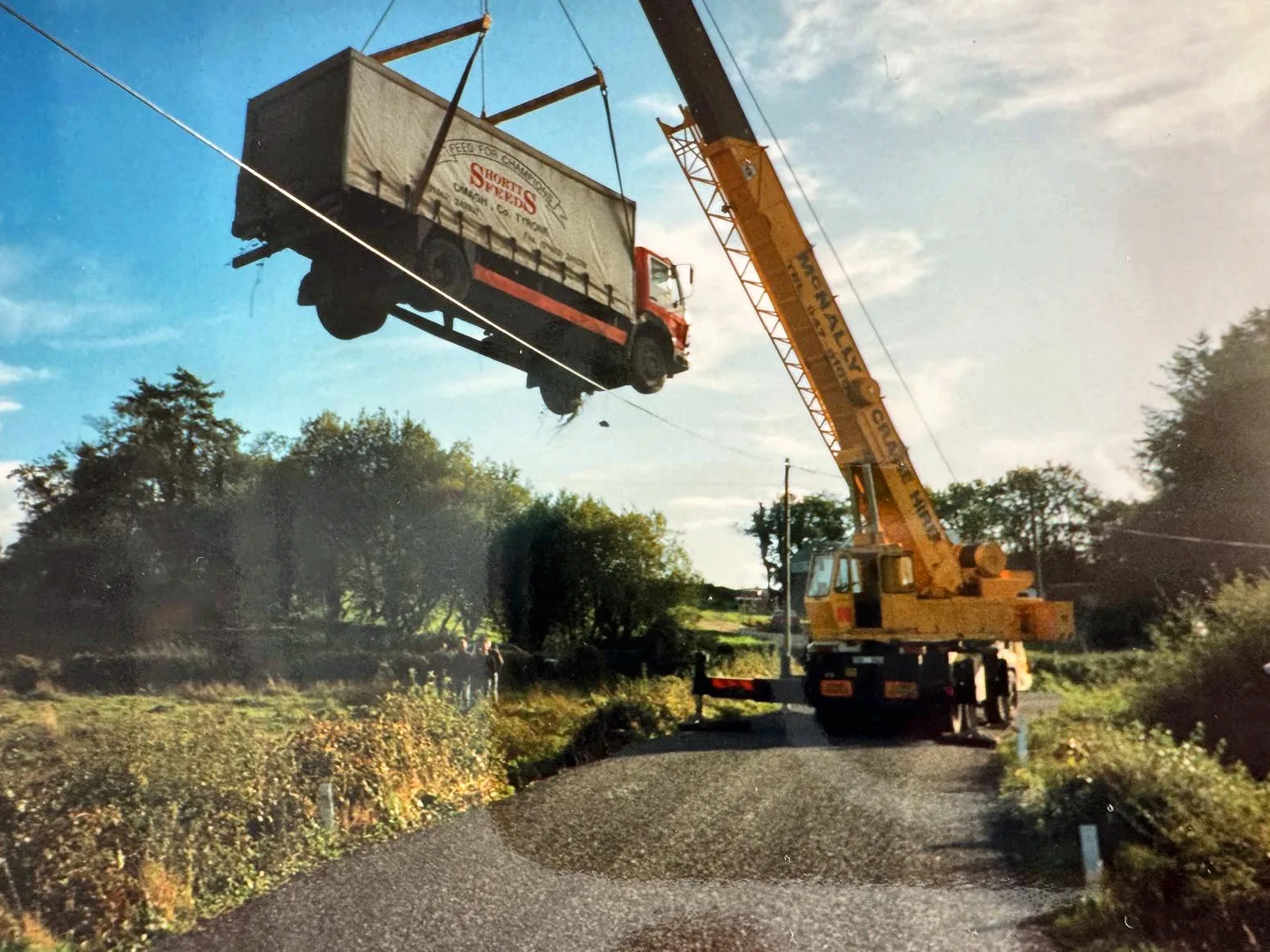 Archive photograph of a McNally’s crane lifting a box lorry clear of a country road