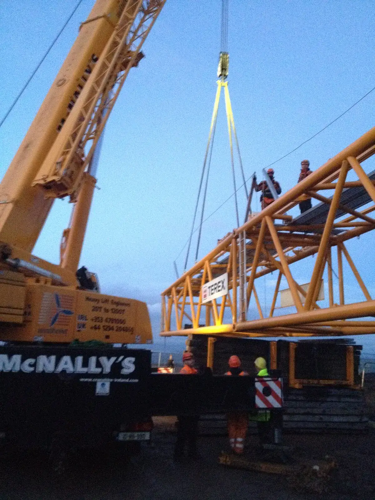 Crane hoisting a lattice boom section into place