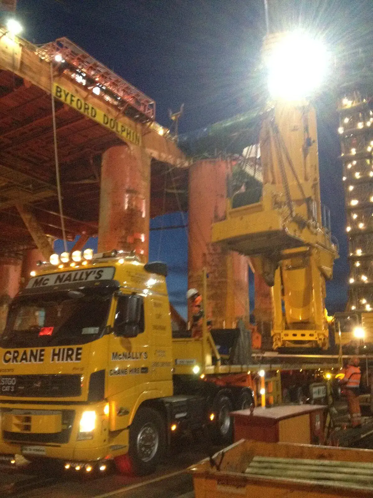Crane truck and crane parked under floodlights at night