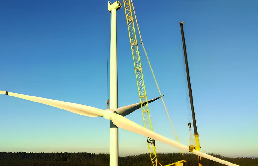 Lattice crane lifting a turbine rotor into place at dusk
