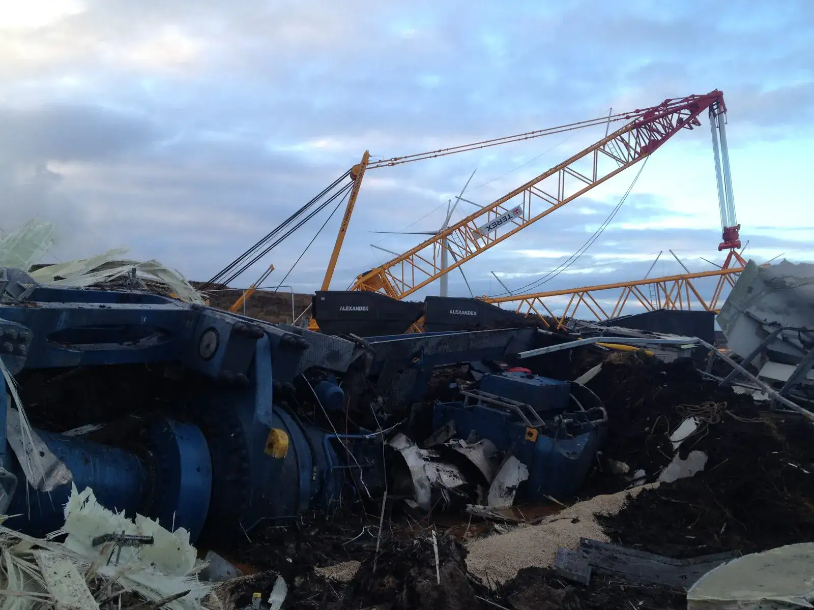 Turbine components on the ground with a red lattice crane behind