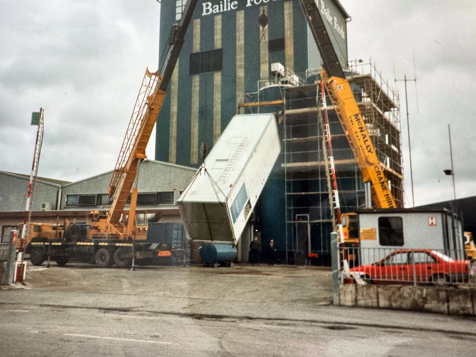 Archive photograph of two McNally’s cranes lifting a building section at a factory