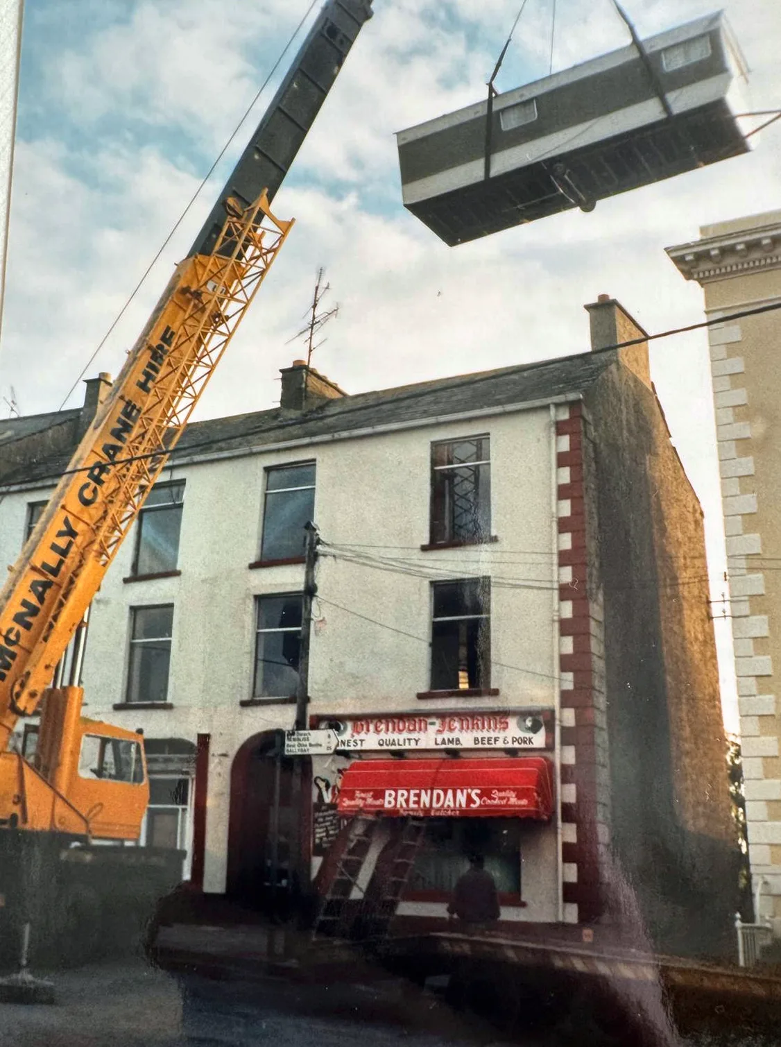 Archive photograph of a McNally’s crane lifting over a shopfront in town
