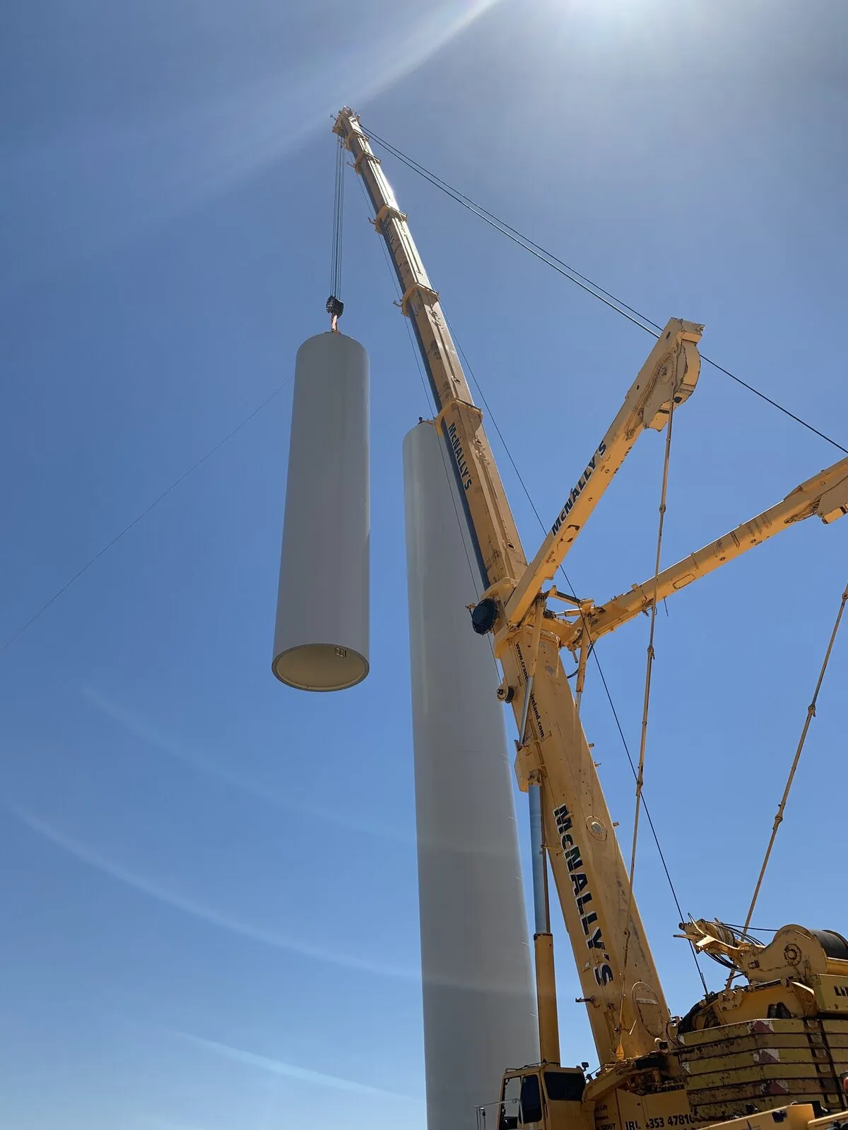 McNally’s crane lifting a turbine tower section beside the standing tower
