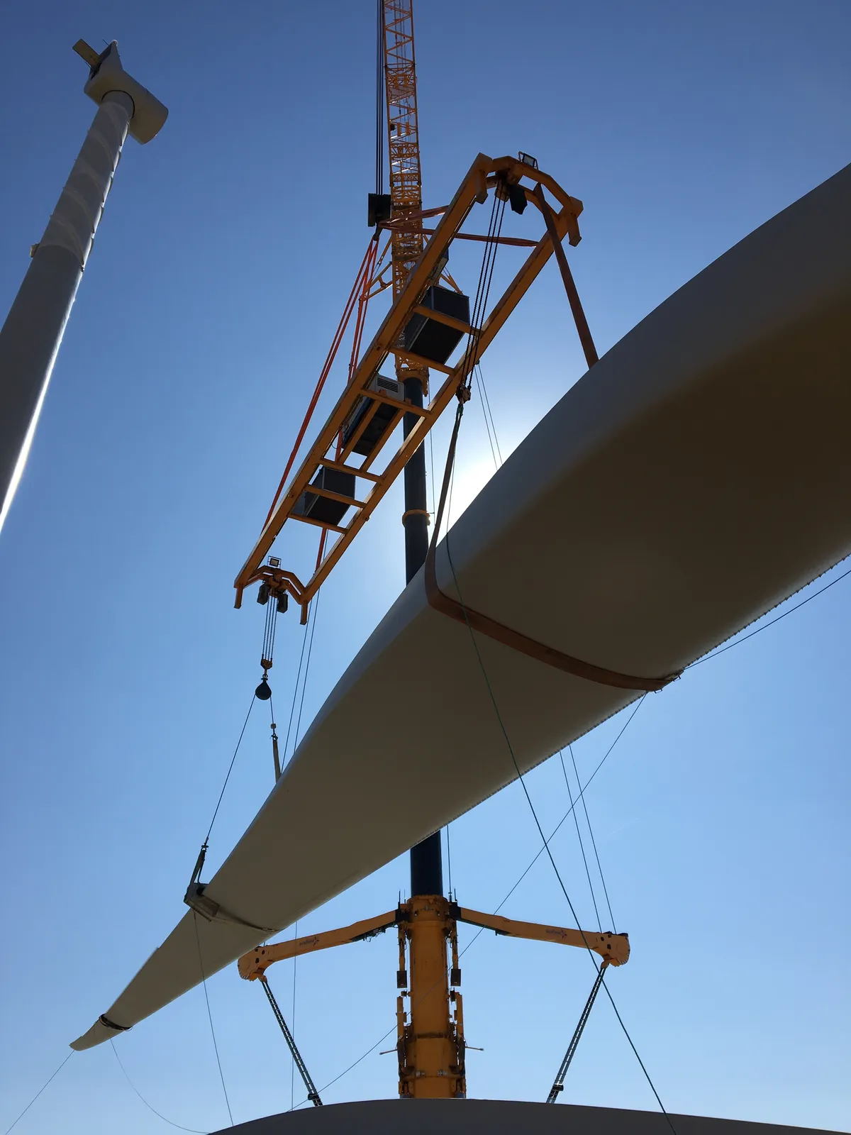 Looking up at a turbine blade lifted by crane